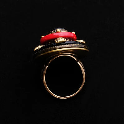 Bague "Merveille d'Antan" en agate noire et rouge avec des détails dorés, vue de côté sur fond noir.