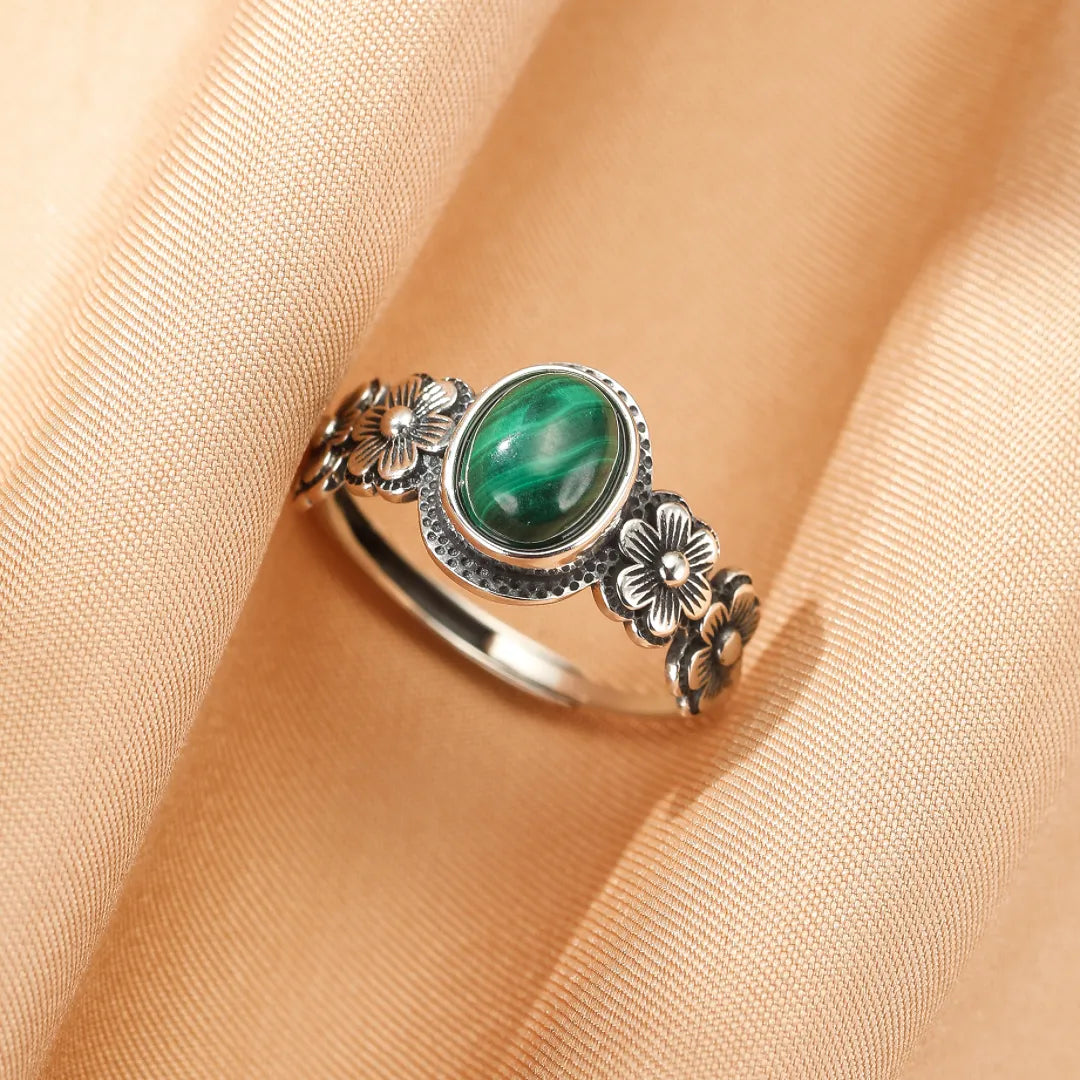 Bague "Essence Florale" en argent avec une pierre de malachite ovale au centre, ornée de petites fleurs sculptées sur l'anneau.