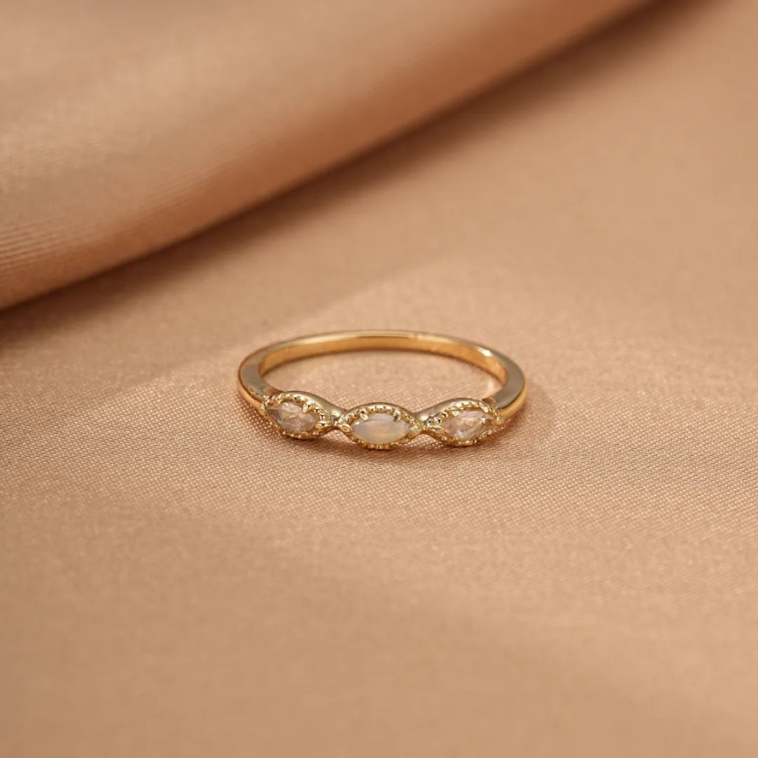 Bague fine en argent doré à l'or, ornée de trois opales marquises disposées en ligne, créant un effet d'alliance lumineuse.