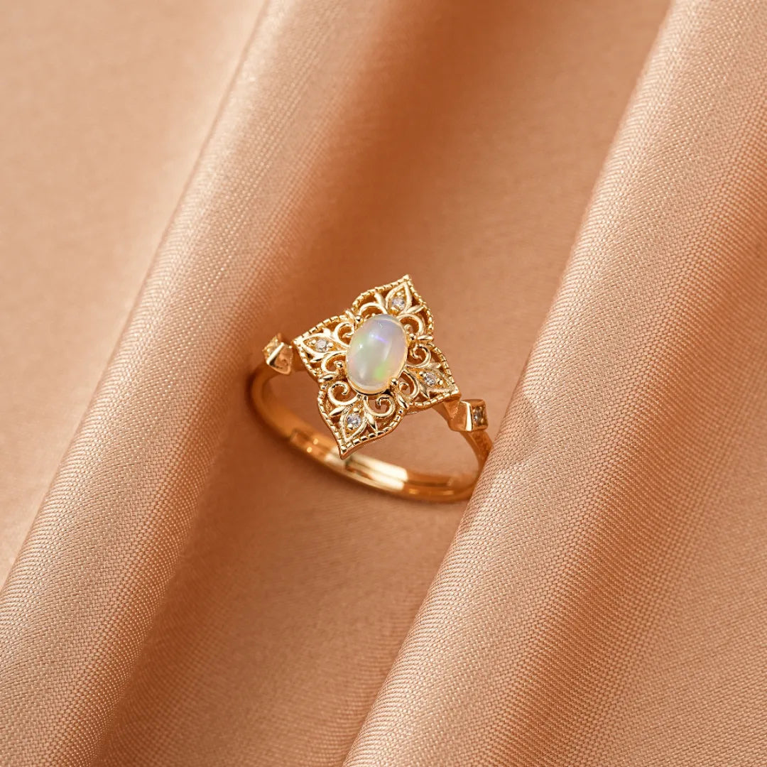 Bague en argent doré or 10K avec une opale centrale ovale entourée de délicats motifs floraux et de petits diamants étincelants.