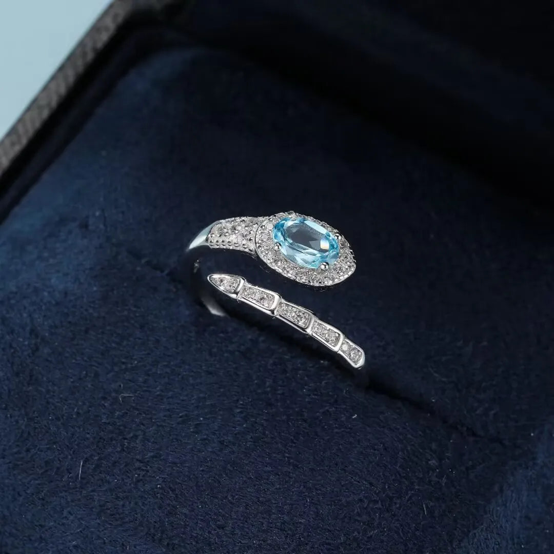 Bague serpent torsadée en argent 925 sertie d'une topaze bleue ovale entourée de petits zirconiums blancs brillants.