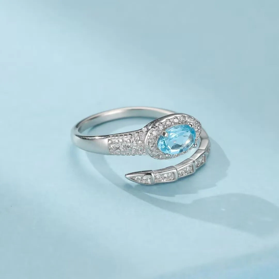 Bague serpent en argent 925 ornée d'une topaze bleue ovale entourée de petits zircons et d'une queue articulée ornée de zircons.