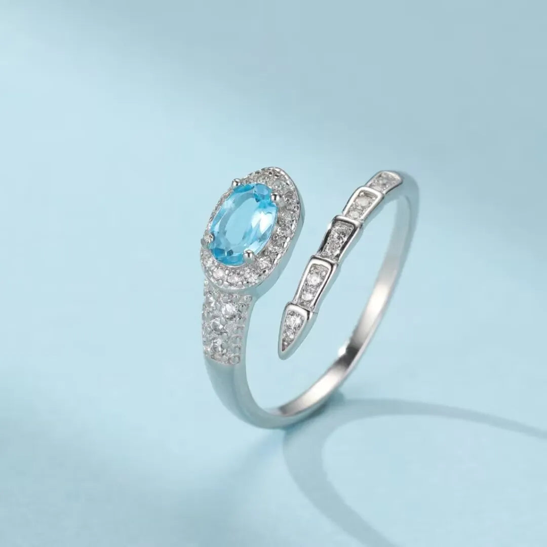 Bague serpent en argent 925 sertie d'une topaze bleue ovale entourée de petits cristaux scintillants, design unique inspiré de la renaissance.
