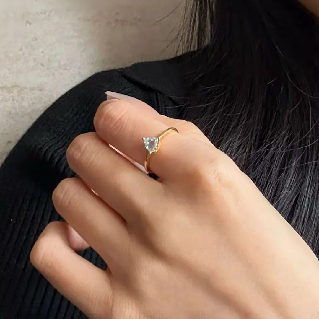 Bague fine en argent doré à l'or 18 carats ornée d'une topaze bleue en forme de cœur, la bague Clarté Céleste portée à la main.