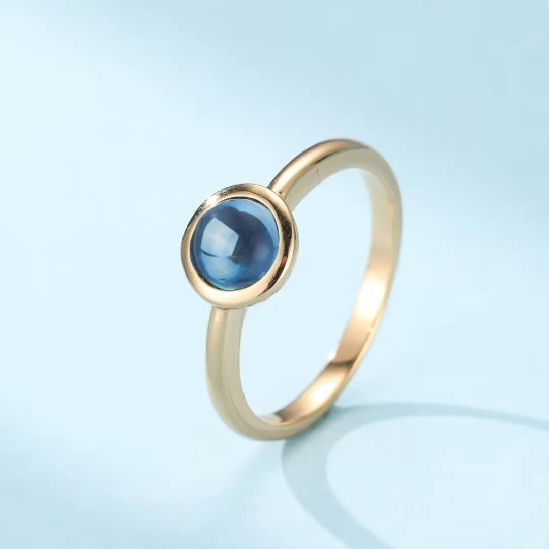 Bague en argent doré or sertie d'une topaze bleue ronde et lumineuse, style "Éclat de l'Aube"