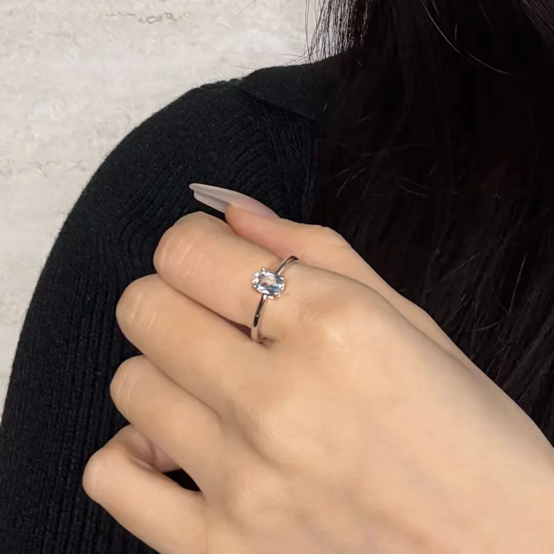 Bague en argent 925 avec une topaze ovale bleue, modèle Élégance Pure, portée au doigt.