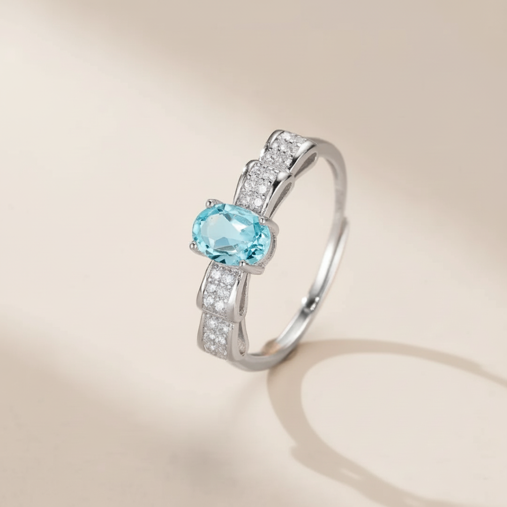 Bague en argent 925 sertie d'une topaze bleue ovale entourée de petites pierres scintillantes, design nœud papillon.
