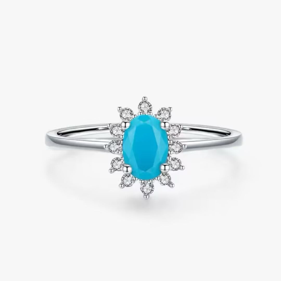 Bague en argent 925 avec une turquoise ovale bleue au centre, entourée de petits zircons blancs disposés en étoile. Design "Fleur Marine".