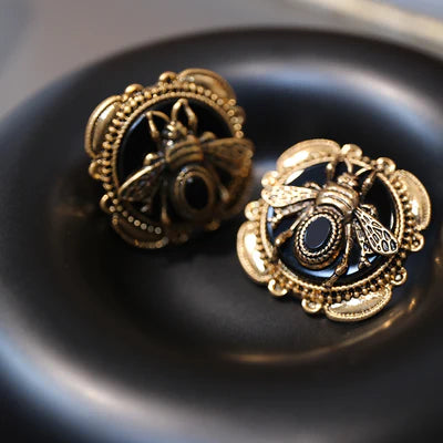 Boucles d'oreilles ornées d'une abeille dorée sur fond noir, avec des détails en agate.