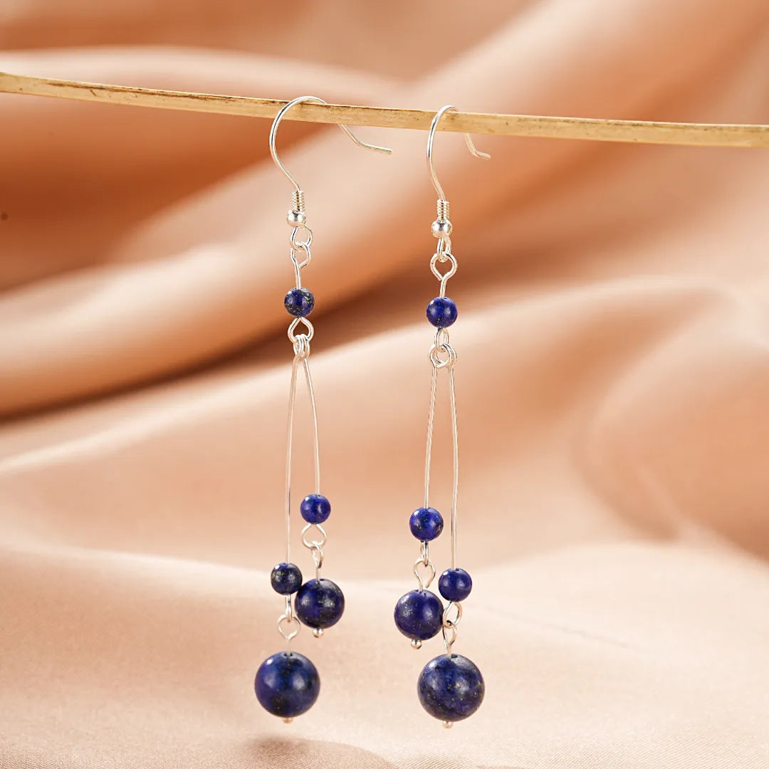 Boucles d'oreilles longues en argent avec des perles de lapis-lazuli bleues de différentes tailles, suspendues à des fils fins.