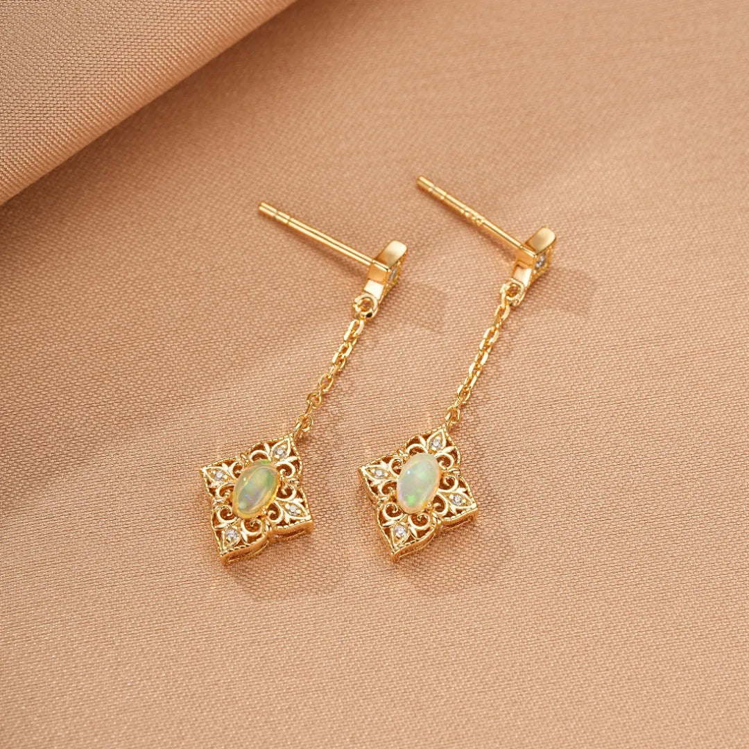 Boucles d'oreilles pendantes en argent doré 10 carats avec opale centrale et détails de diamants, ornées d'un motif floral antique.