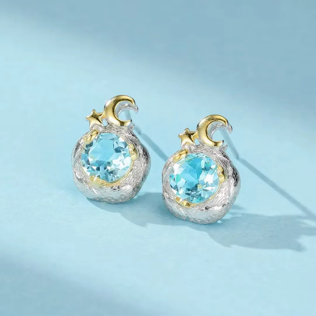 Boucles d'oreilles en argent 925 serties de topaze bleue, ornées d'un croissant de lune doré et d'étoiles.