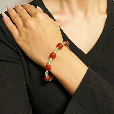 Bracelet "Fraîcheur Colorée" composé de perles d'agate rouge et de quartz fraise vert sur un poignet féminin.