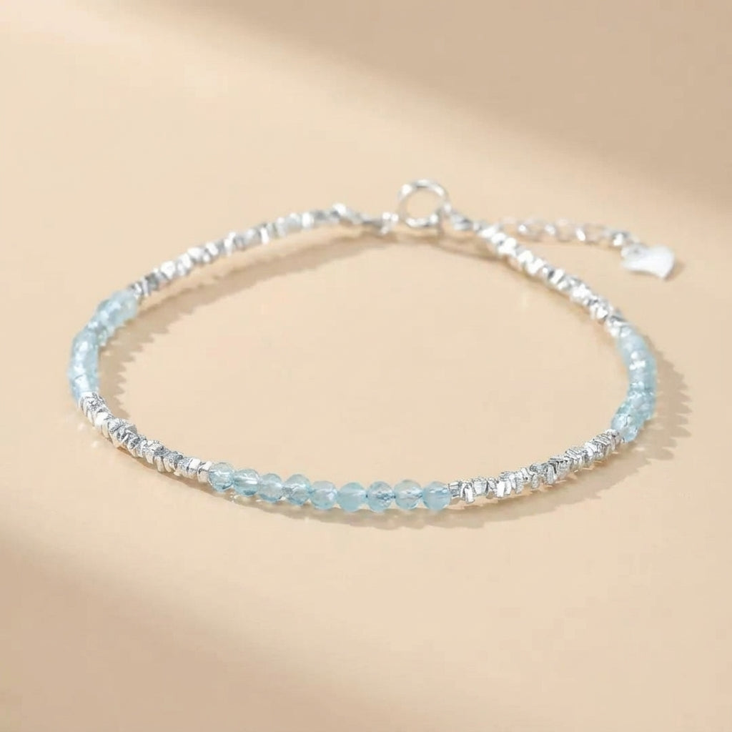 Bracelet fin en argent 925 avec des petites pierres d'aigue-marine bleues et des perles argentées facettées, fermoir mousqueton.