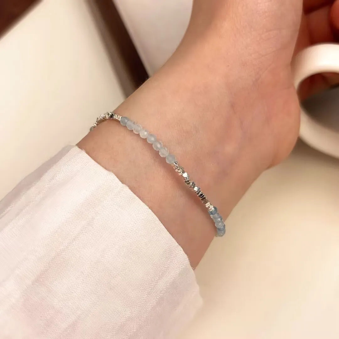 Bracelet fin "Murmure Douce" en argent et perles d'aigue-marine bleu clair porté à la cheville.
