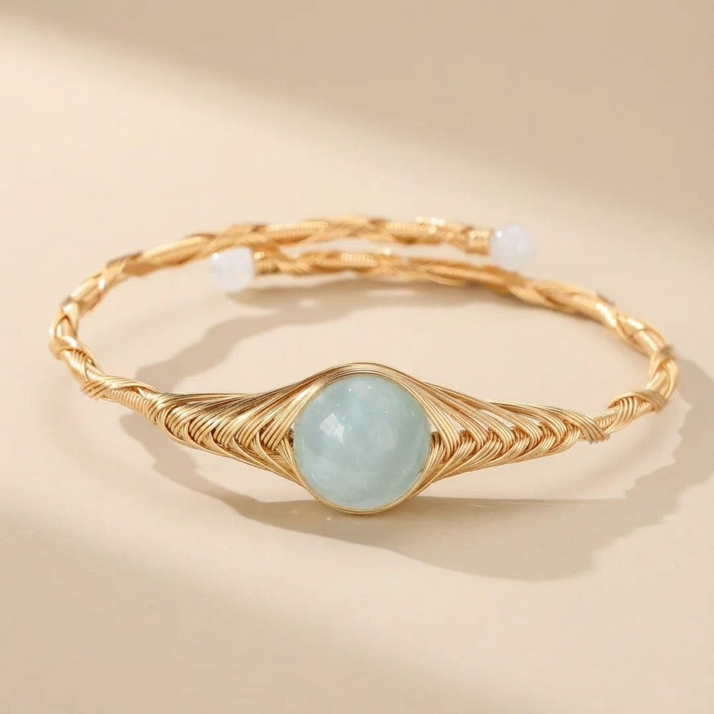 Bracelet jonc torsadé doré à l'or 14K avec une aigue-marine bleue pâle centrale et deux petites perles blanches aux extrémités.