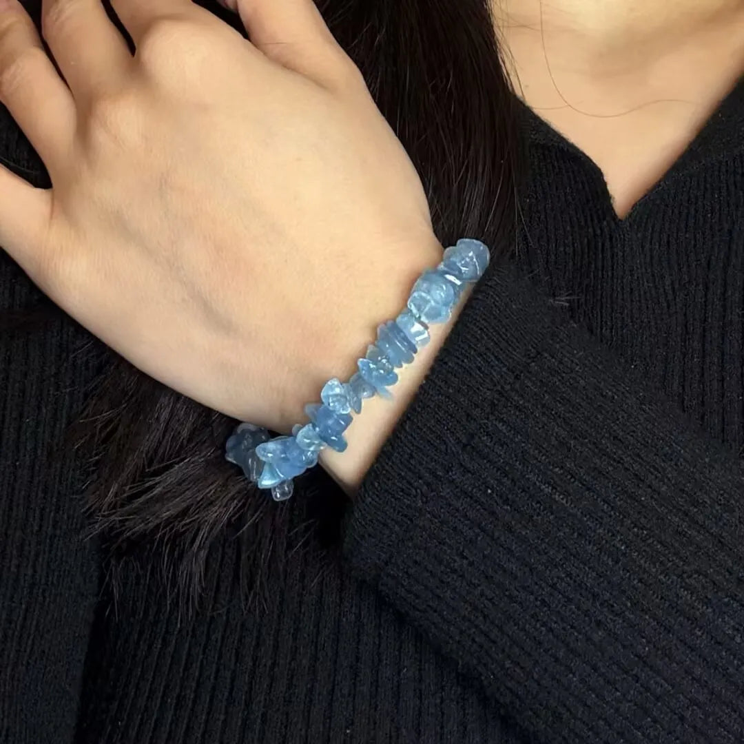 Bracelet "Trésor Marin" en aigue-marine bleue, style bohème, sur le poignet d'une femme portant un pull noir.