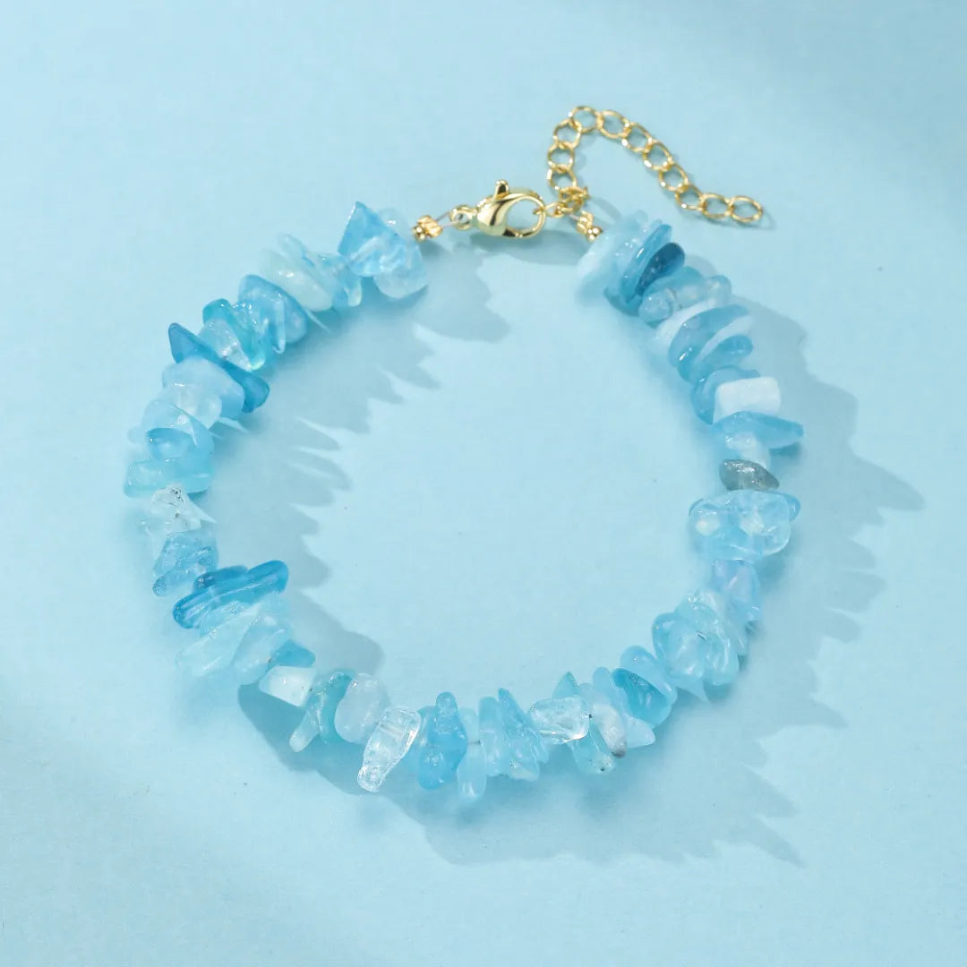 Bracelet "Trésor Marin" fait de pierres d'aigue-marine brutes et irrégulières, serties sur une chaîne dorée réglable avec fermoir mousqueton.