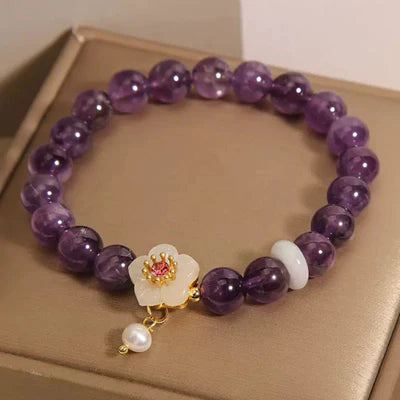 Bracelet "Fleur d'Harmonie" en améthyste, jade et perle, avec une breloque fleur blanche ornée de pierres roses et d'une perle nacrée.