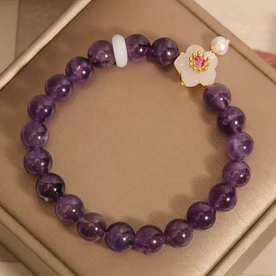 Bracelet "Fleur d'Harmonie" en améthyste violette, jade blanc et perle, orné d'une breloque fleur avec un centre rose.