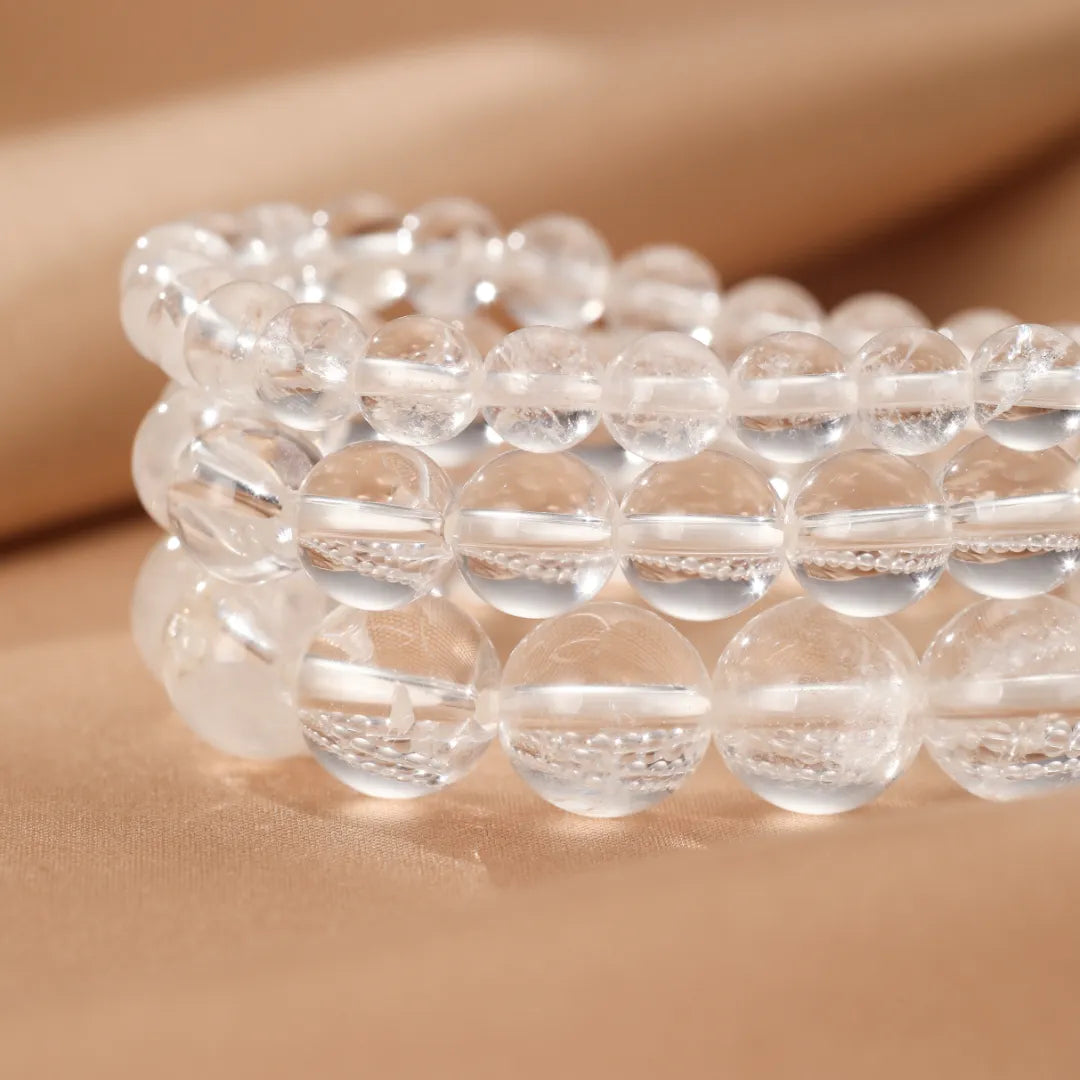 Bracelet Cristal de Roche "Clarté Pure" en perles transparentes, présenté en gros plan sur un fond beige doux.