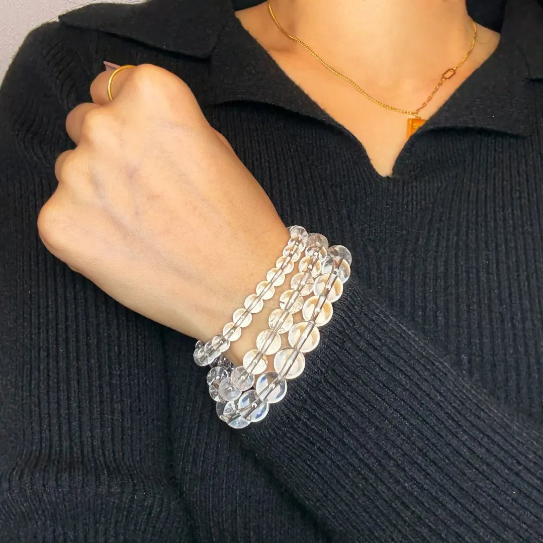 Bracelet Cristal de Roche "Clarté Pure" composé de plusieurs rangées de perles rondes transparentes et facettées, porté au poignet d'une femme.