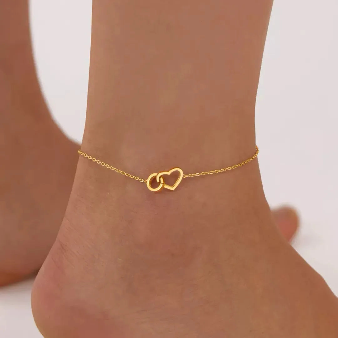 Bracelet de cheville doré avec deux cœurs entrelacés, symbole d'amour fort.