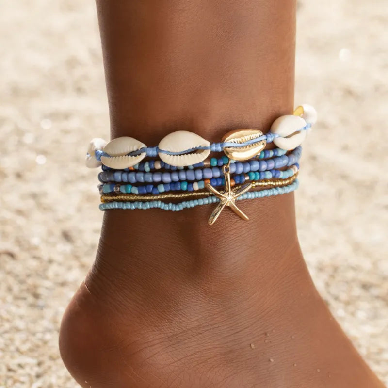 Bracelet de cheville "Énergie Marine" composé de plusieurs rangées de perles bleues, dorées et turquoise, orné de coquillages et d'une breloque étoile de mer dorée.