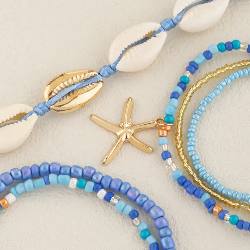 Ensemble de bracelets de cheville "Énergie Marine" ornés de coquillages cauris, d'une étoile de mer dorée et de perles bleues et dorées.
