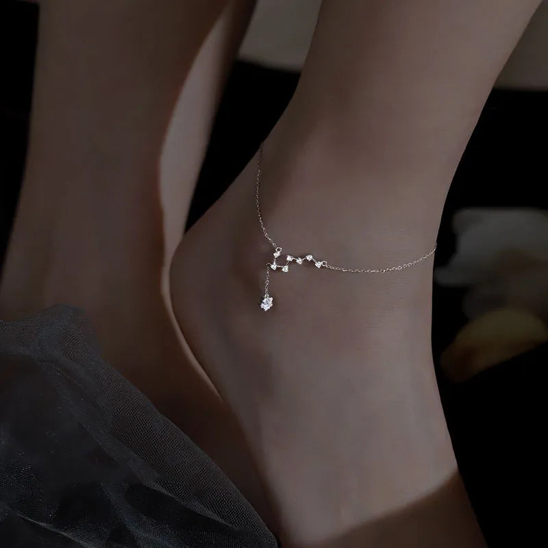 Bracelet de cheville en argent 925 "Étoile Nocturne" avec une petite étoile suspendue, orné de cristaux brillants, porté à la cheville.