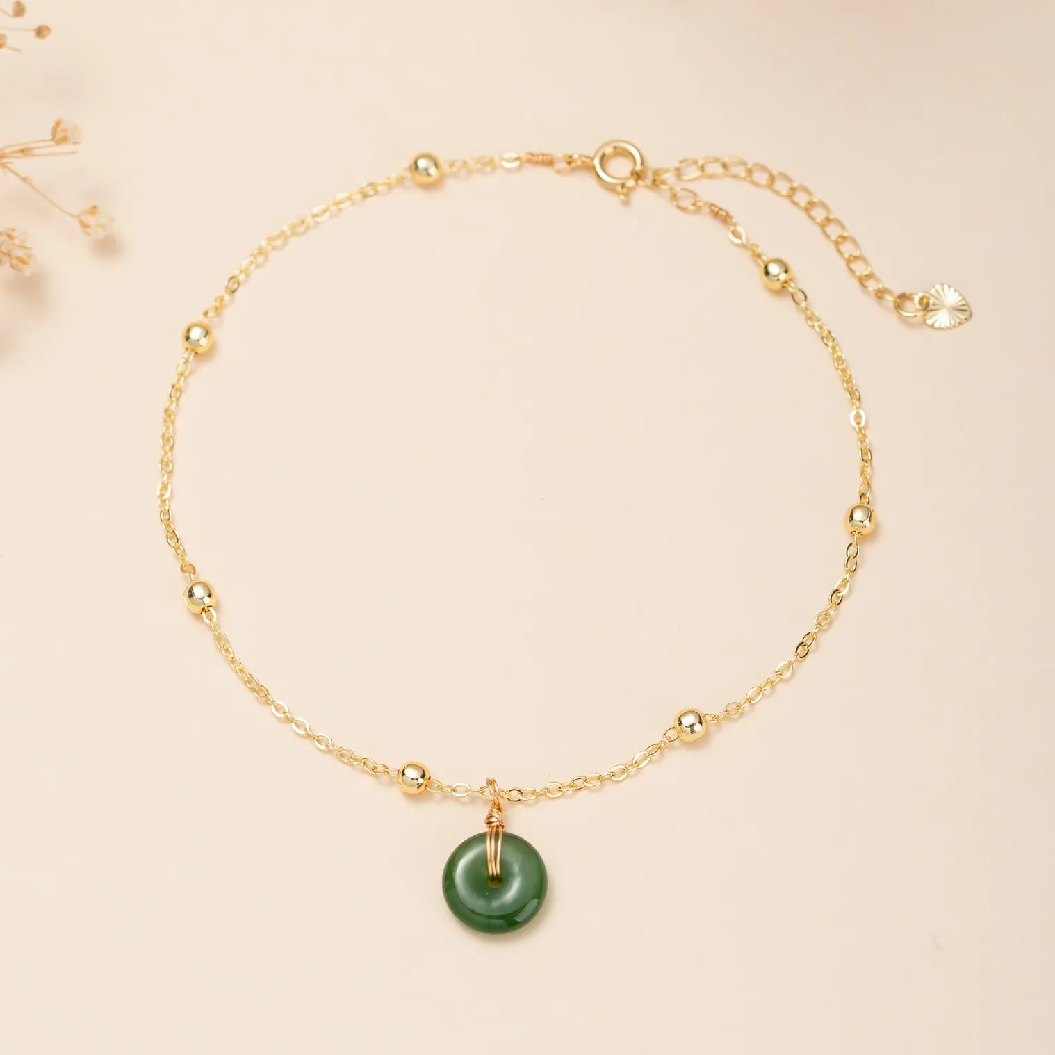 Bracelet de cheville en argent doré or avec une chaîne fine ornée de petites perles dorées et d'un pendentif rond en jade vert "Vert Doux" filé.