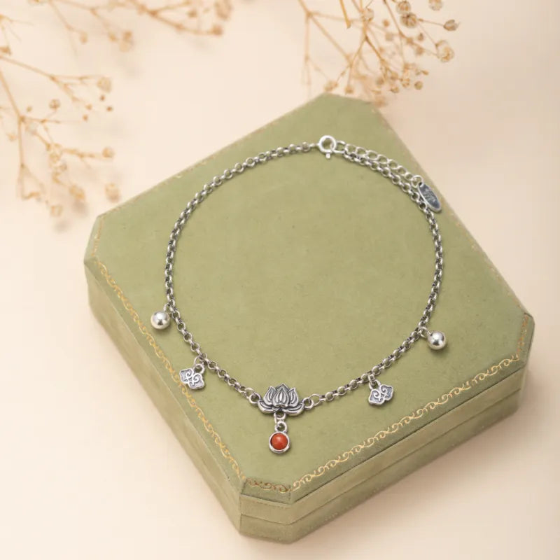 Bracelet de cheville en argent avec un pendentif lotus orné d'une agate rouge, et de breloques nuage et boule.
