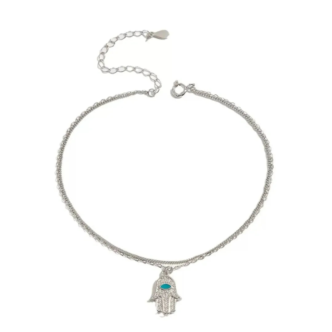 Bracelet de cheville double chaîne en argent avec un pendentif Main de Fatma orné de zircons et d'une pierre bleue.