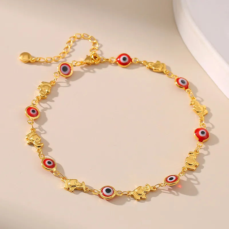 Bracelet de cheville doré "Gardien Mystique" orné de 5 charms œil du mal rouge et noir alternés avec 5 charms éléphant doré.