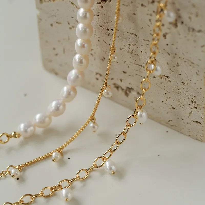 Bracelet de cheville doré à maillons ornés de petites perles nacrées et d'une chaîne de perles baroques.