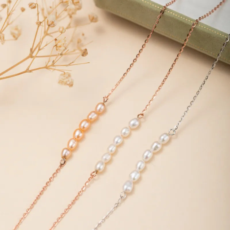 Trois bracelets de cheville en argent avec des perles, dont un bracelet avec des perles roses pâles, un bracelet avec des perles blanches et un bracelet avec des perles ivoire.