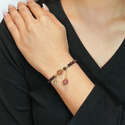 Bracelet "Merveille Papillon" en grenat et quartz fraise, orné d'une breloque papillon et d'une goutte de quartz fraise.