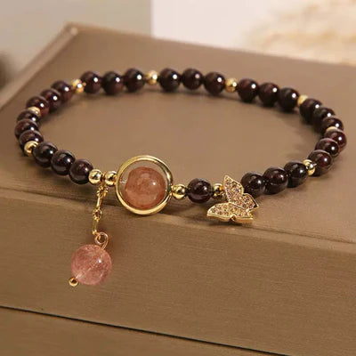 Bracelet "Merveille Papillon" en grenat et quartz fraise, orné d'un pendentif papillon doré et de perles rondes.