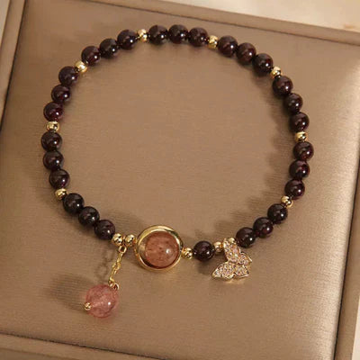 Bracelet "Merveille Papillon" en grenat et quartz fraise avec un charmant pendentif papillon incrusté de cristaux et une perle rose suspendue.