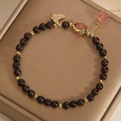 Bracelet "Merveille Papillon" en grenat et quartz fraise, avec un fermoir papillon serti de strass et une pierre centrale ovale orangée.