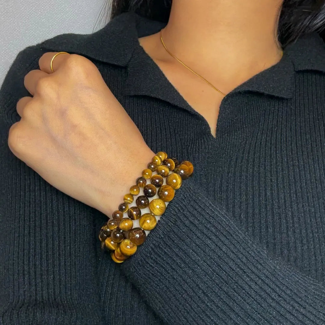 Bracelet "Force Pure" en Œil de Tigre, composé de plusieurs rangées de perles de différentes tailles, porté au poignet d'une personne portant un pull noir.