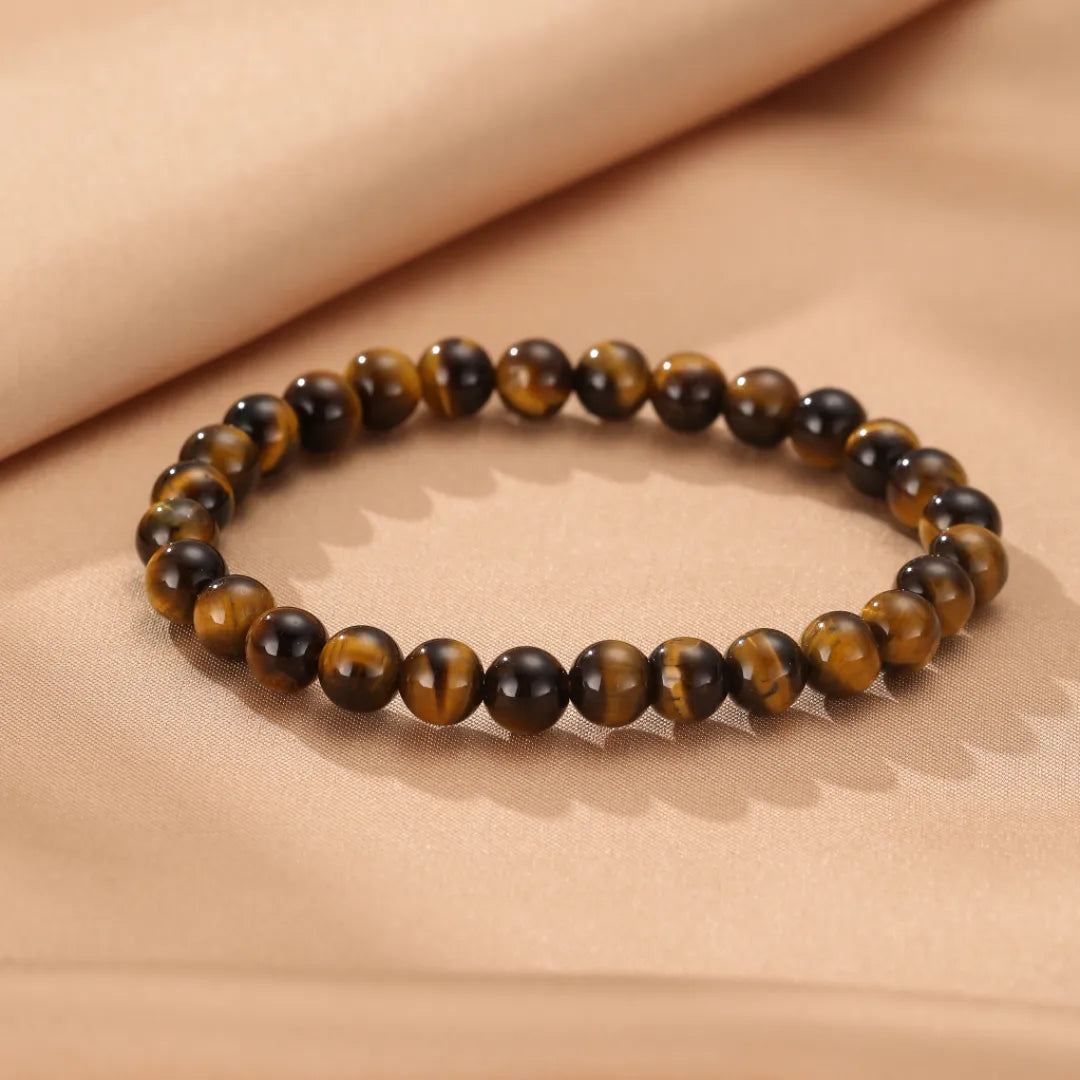 Bracelet "Force Pure" en œil de tigre, composé de perles naturelles marron et dorées, sur un fond beige.