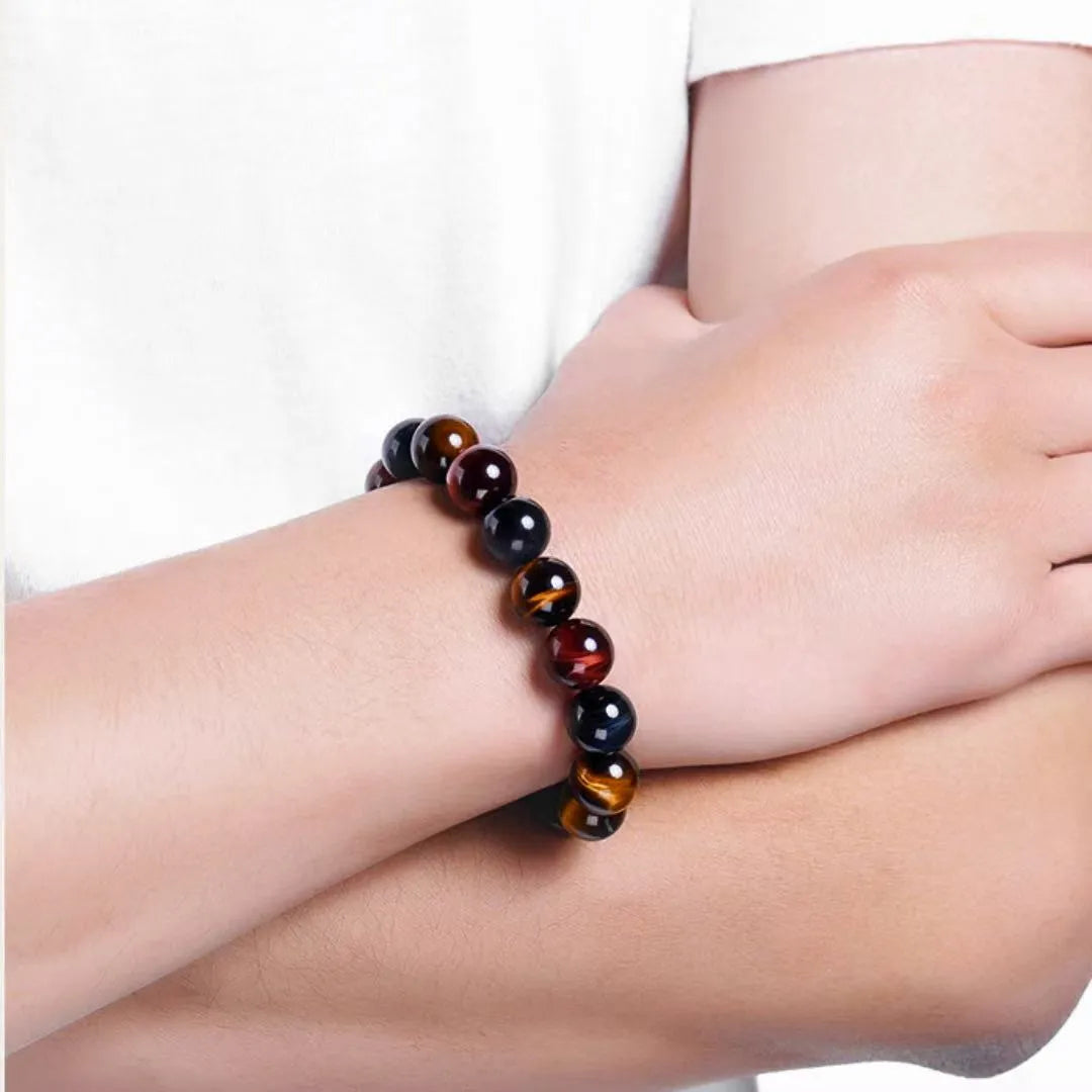 Bracelet œil de tigre multicolore "Reflets d'Équilibre" porté au poignet d'une personne, montrant les perles rondes aux couleurs variées marron, rouge et bleu.