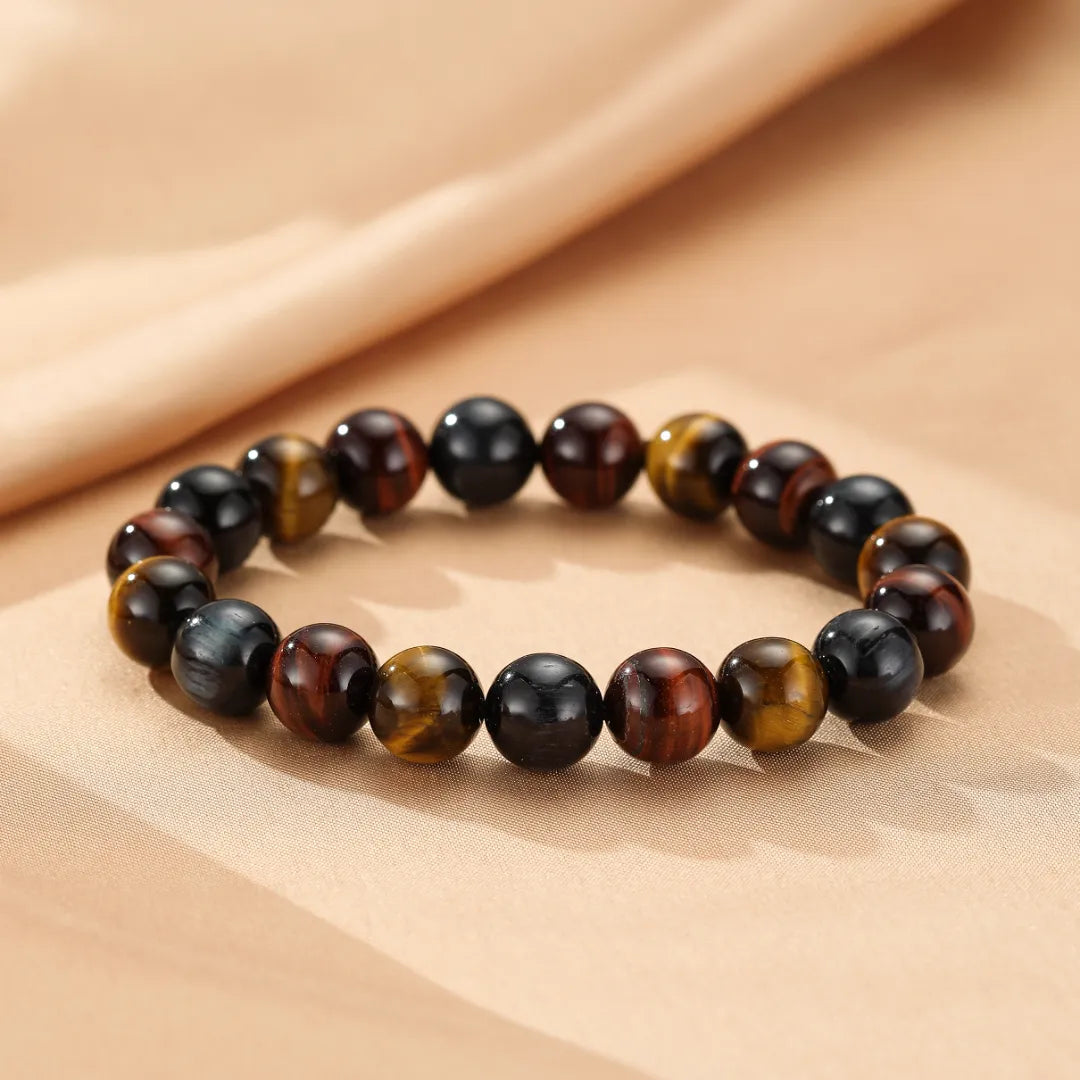 Bracelet "Reflets d'Équilibre" en œil de tigre multicolore, composé de perles rondes marron, dorées et noires.