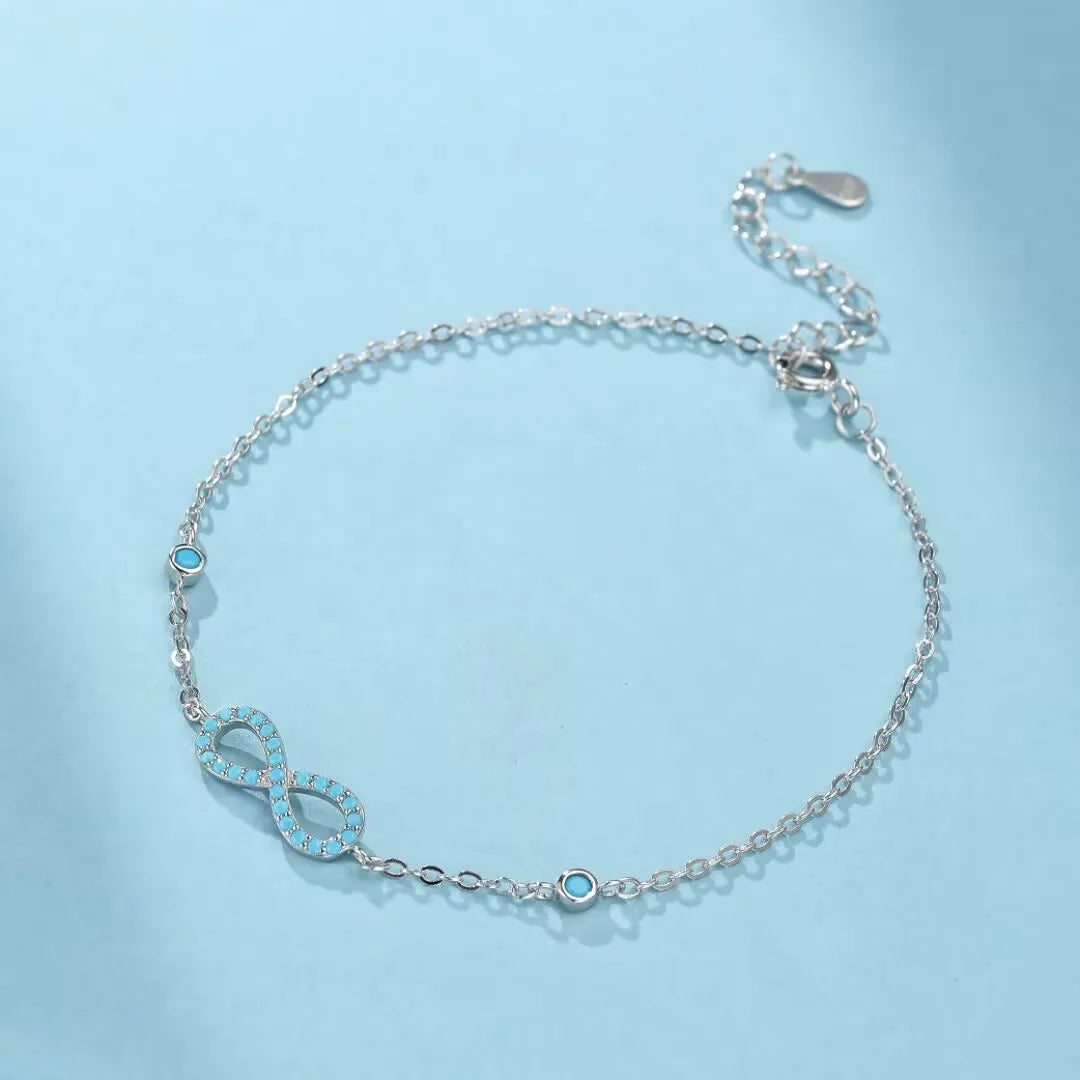 Bracelet infini turquoise "Souffle d'Infini" en argent 925, orné de petites pierres turquoise bleues le long de la chaîne.