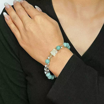 Bracelet "Clarté Apaisante" en jade bleu turquoise et cristal de roche transparent, porté au poignet d'une femme.