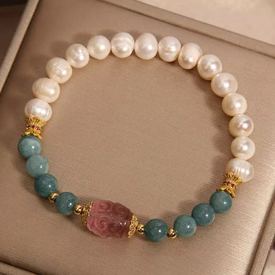 Bracelet artisanal en perles de jade, perles d'eau douce blanches et une pierre centrale sculptée rose, rehaussé d'éléments dorés.