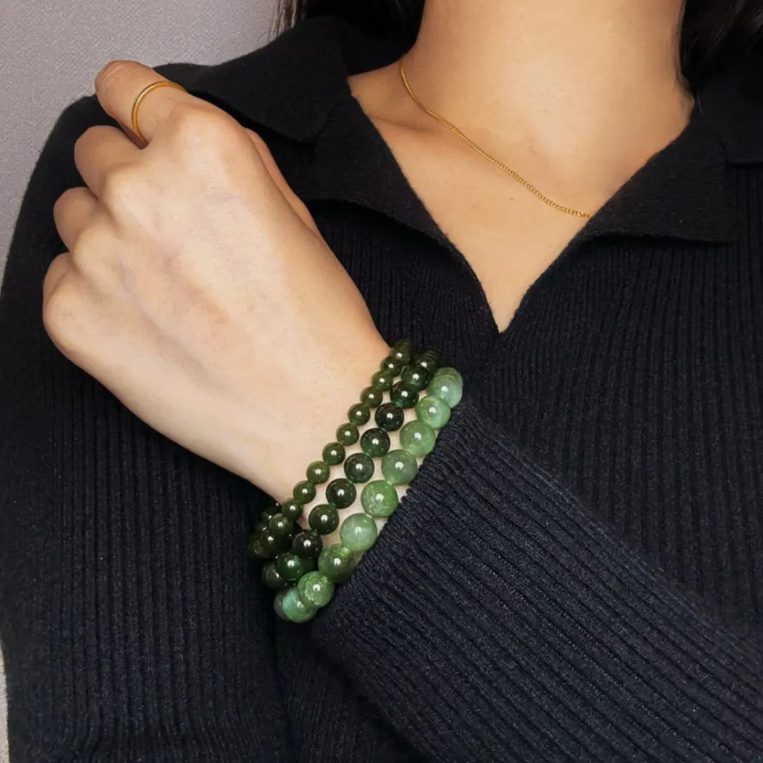 Trois bracelets en perles de jade vert de différentes tailles, portés sur le poignet d'une femme