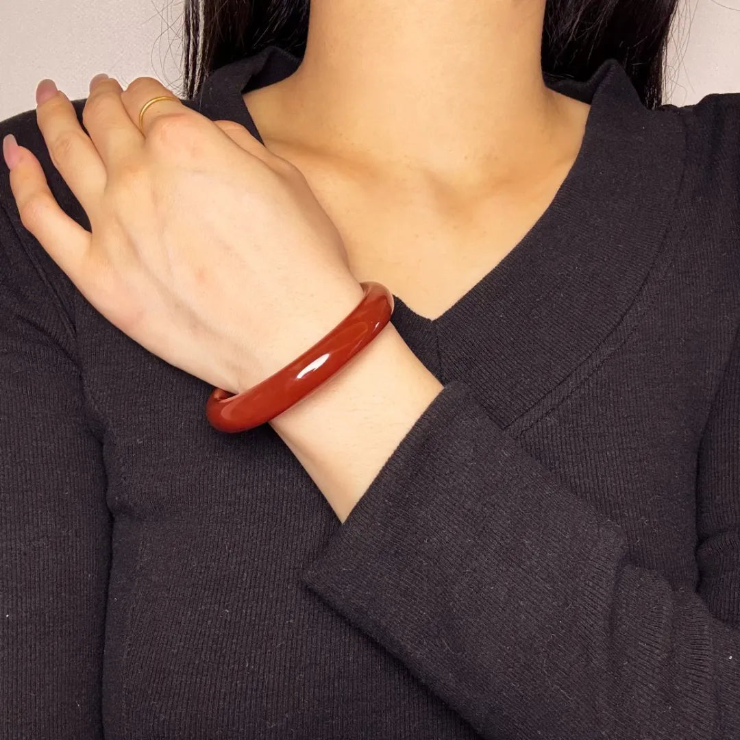 Bracelet jonc en agate rouge profond "Force Audacieuse" porté au poignet d'une femme.
