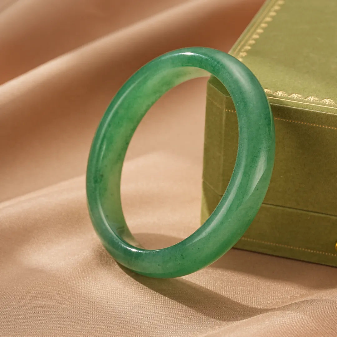 Bracelet jonc en aventurine verte "Énergie Vitale" sur un fond satiné beige, présentation dans un écrin vert.